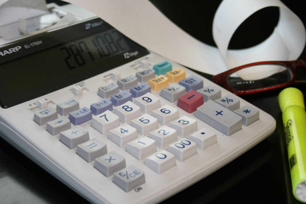 Calculator with aribbon next to pair of glasses and a high lighter used in preparing bankruptcy petitions