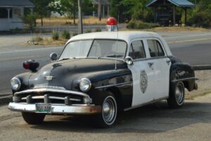 Old classic Black and white police car with red siren on top